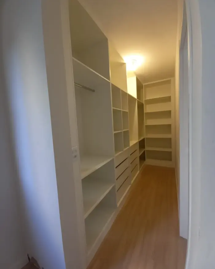 Closet planejado em corredor com prateleiras e cabideiros brancos, projeto Silva Lima Planejados em Santa Luzia
