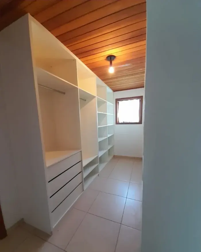 Closet planejado com prateleiras brancas, janela e teto em madeira, projeto Silva Lima Planejados em Santa Luzia
