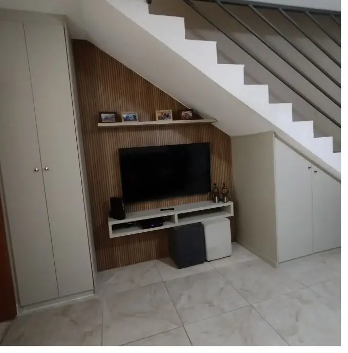 Painel de TV planejado aproveitando o vão embaixo da escada, com nichos e armários laterais, projeto Silva Lima Planejados em Santa Luzia