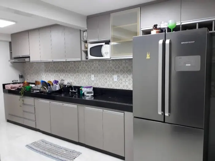 Cozinha planejada com revestimento decorativo e nicho para geladeira, projeto Silva Lima Planejados em Santa Luzia