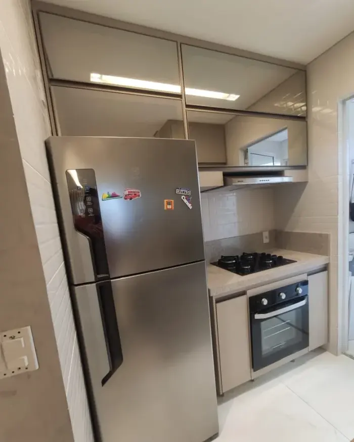 Cozinha planejada com nicho para geladeira, armários com acabamento espelhado e coifa, projeto Silva Lima Planejados em Santa Luzia